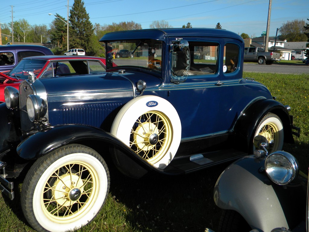 An old blue antique car with whitewall tires